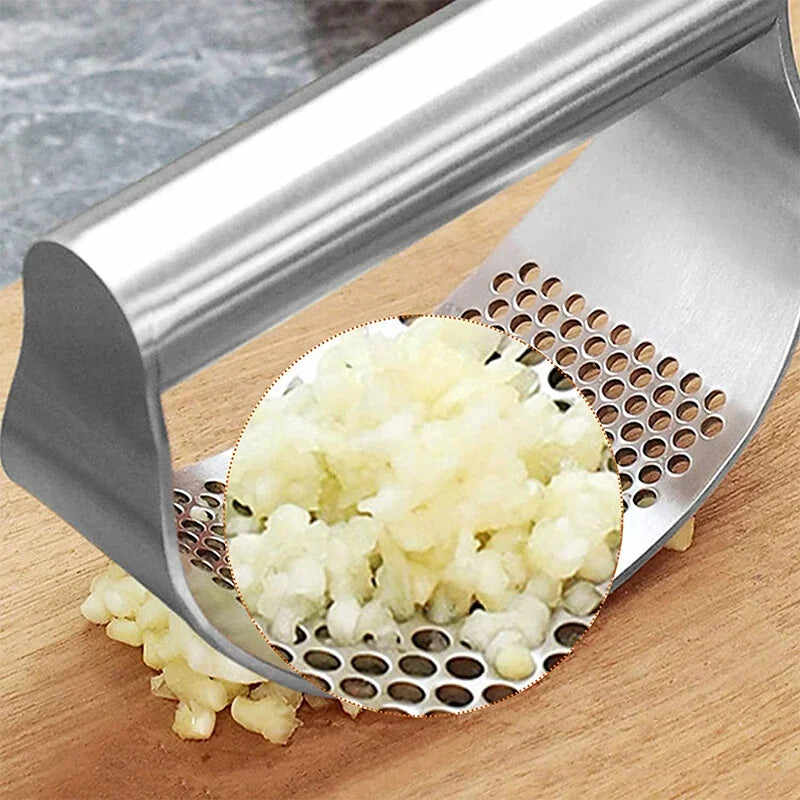 Stainless steel garlic press efficiently mashing garlic cloves into fine pieces on a wooden surface